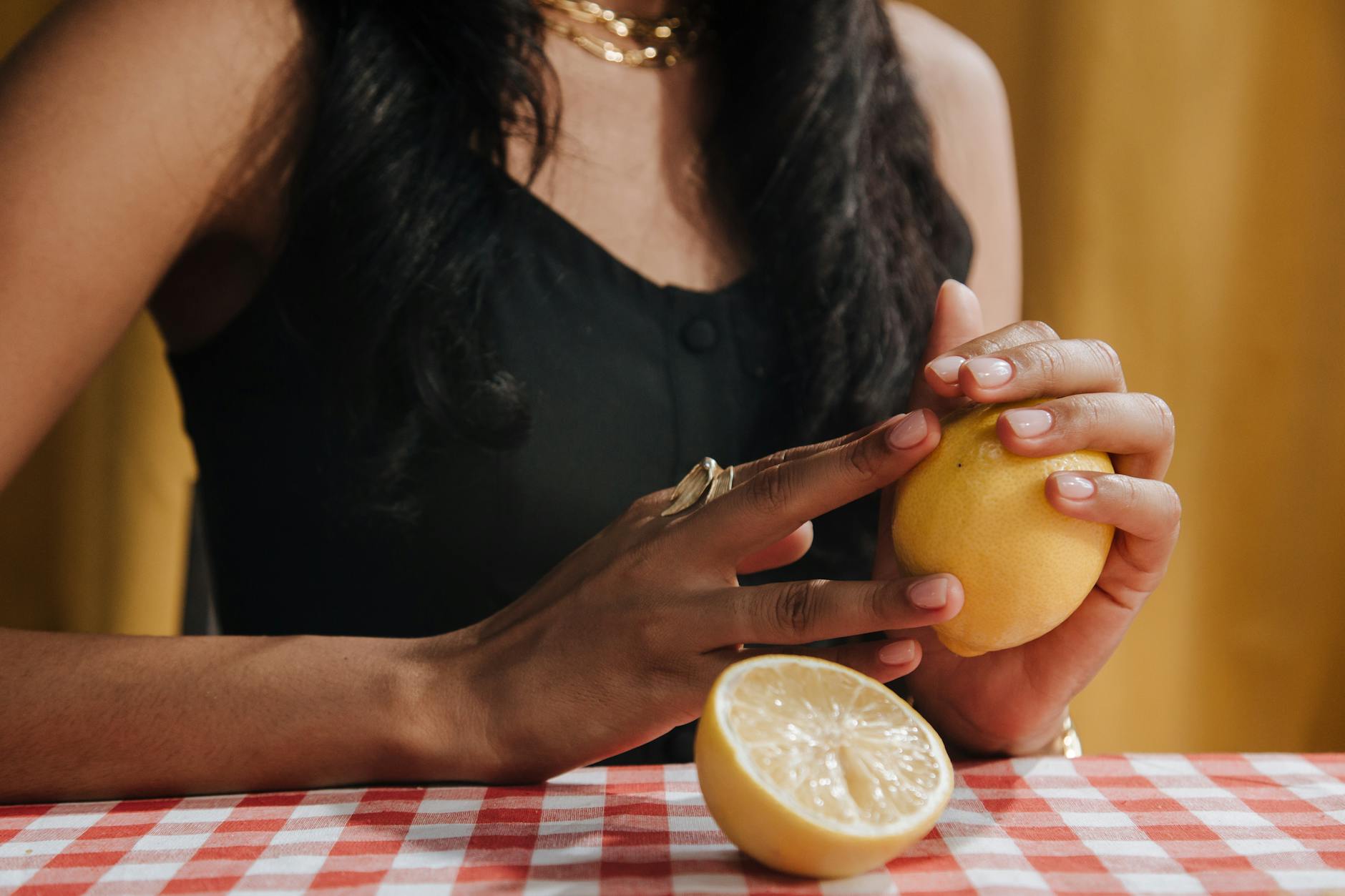 A close-up of a hand holding an orange vibrator against a minimalistic purple backdrop
