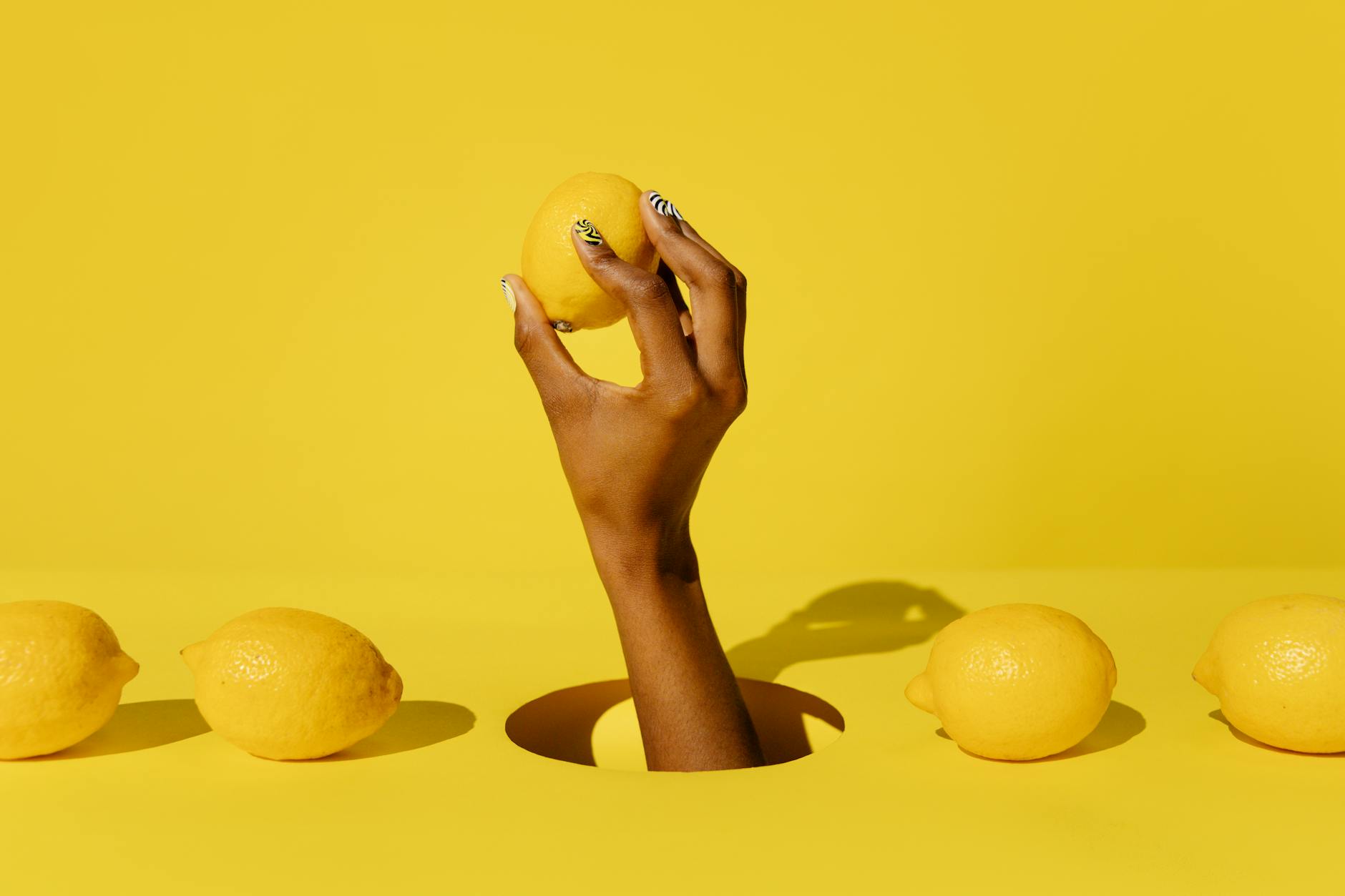 Close-up of a hand holding an orange vibrator against a minimalistic purple backdrop
