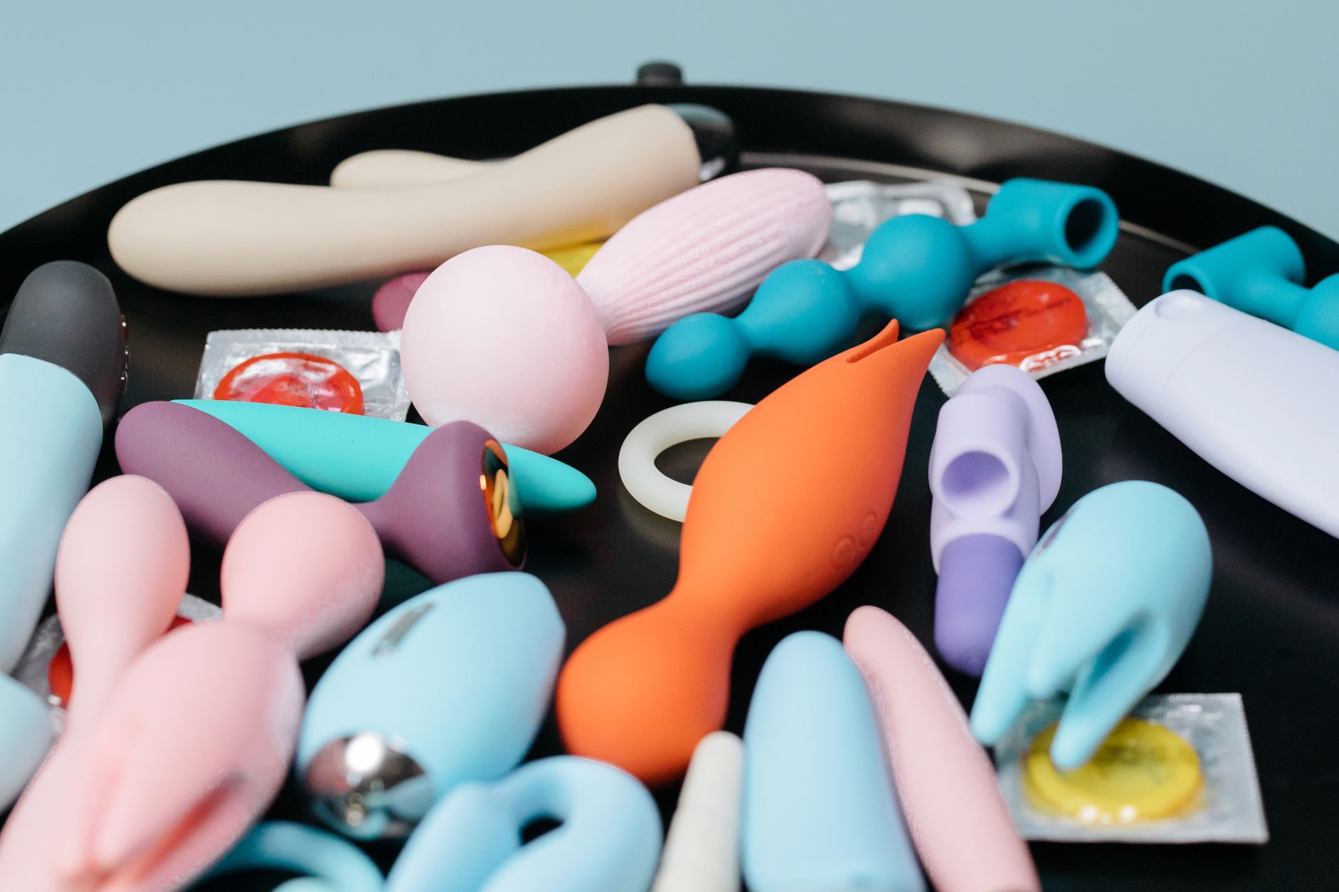 Eine bunte Sammlung verschiedener Vibratoren auf schwarzem Tablett, die moderne sexuelle Wellness zeigt