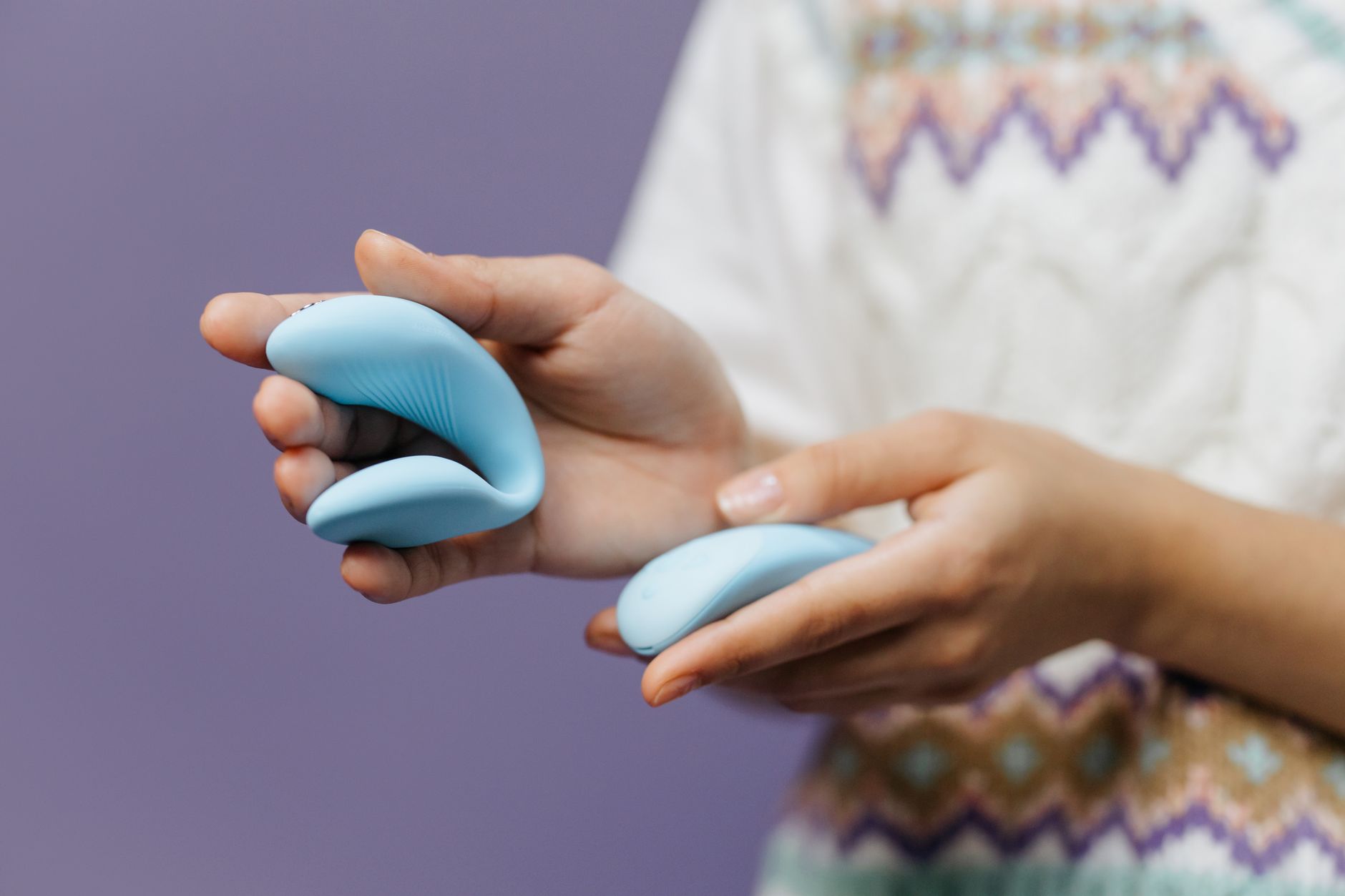 A hand holding a sleek lemon-colored vibrator against a purple background, symbolizing intimate exploration with a partner