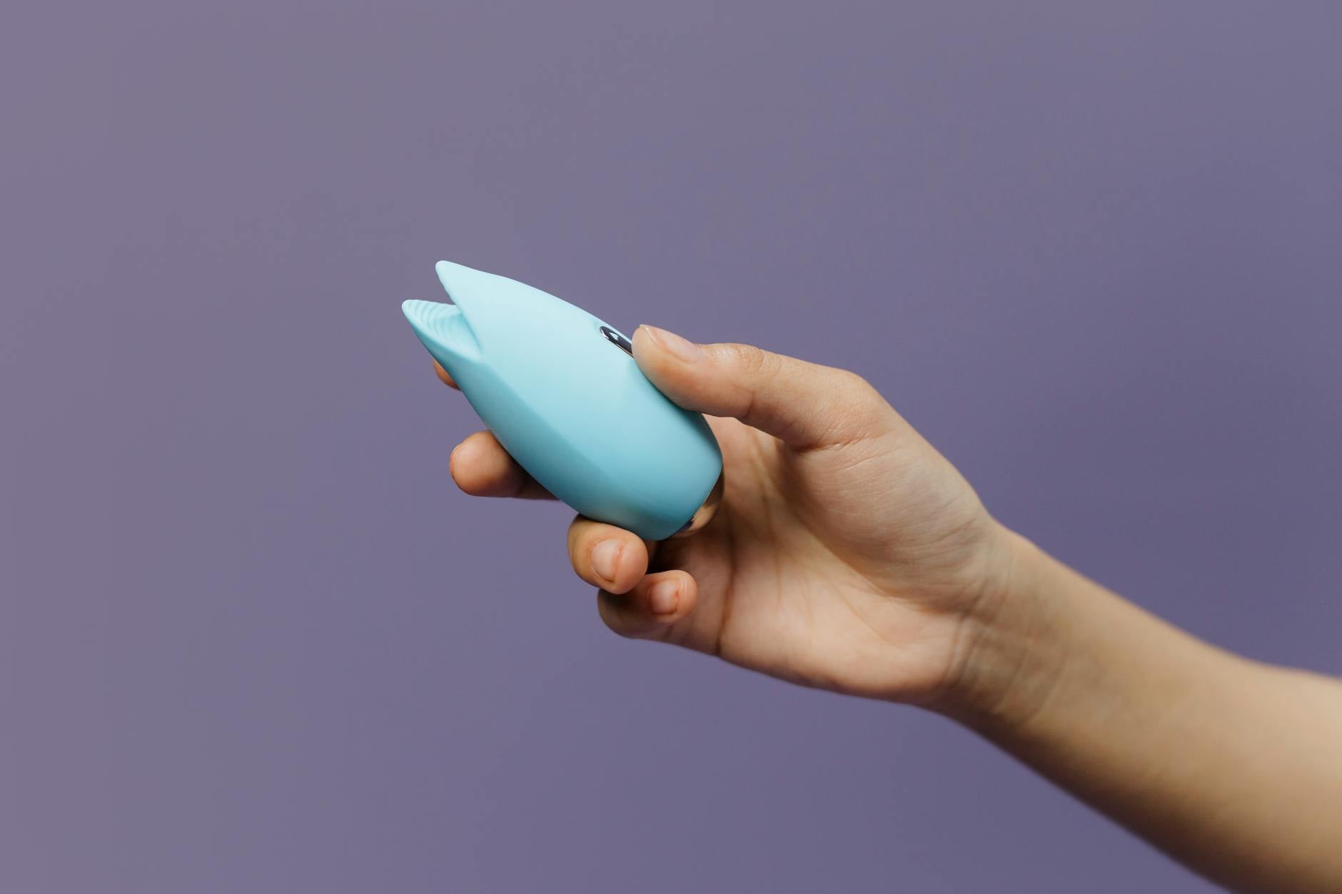 Pink vibrator on purple background with romantic candles and heart confetti