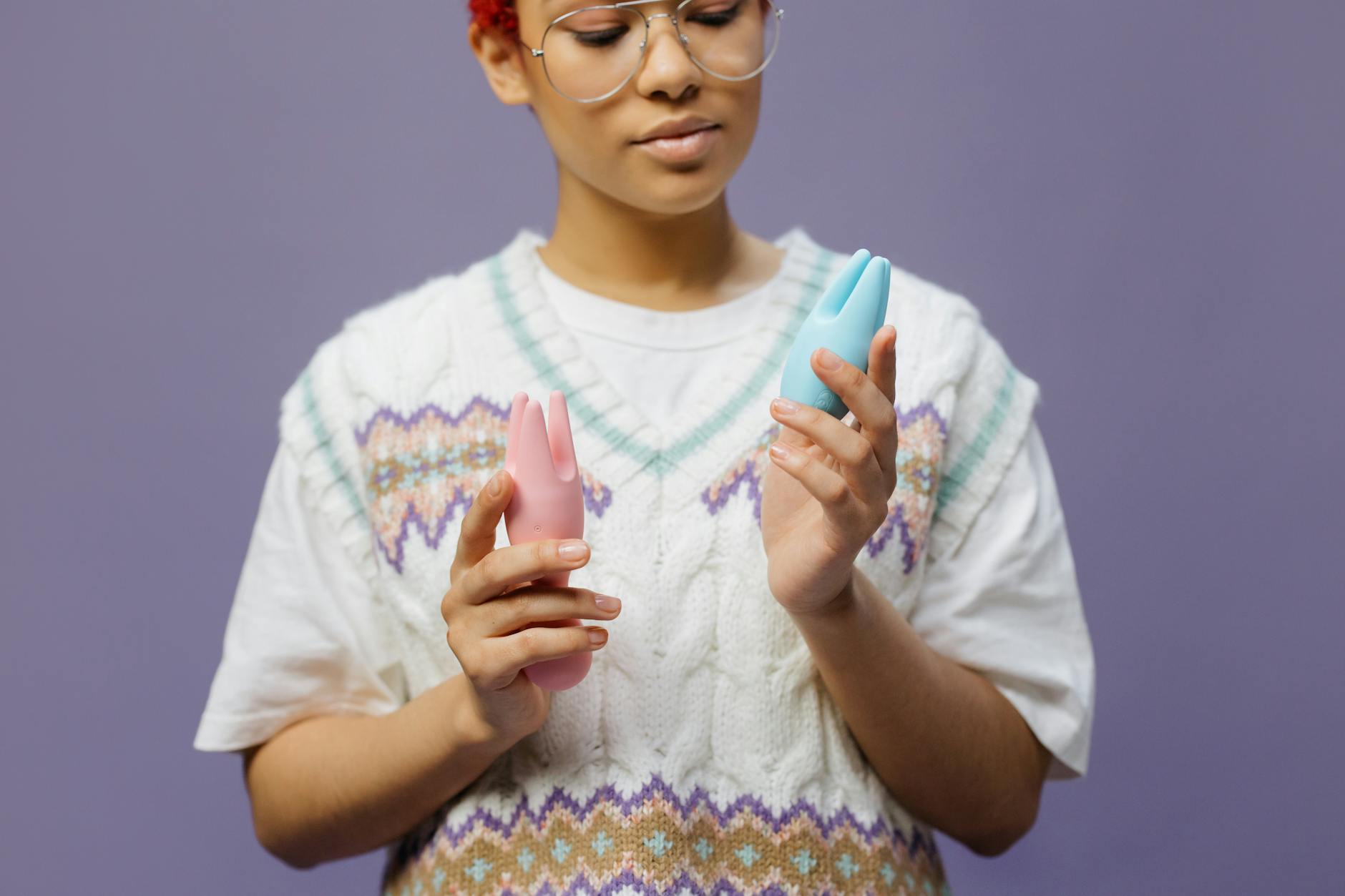Woman holding vibrators with contemplative expression, exploring sensitivity and pleasure options