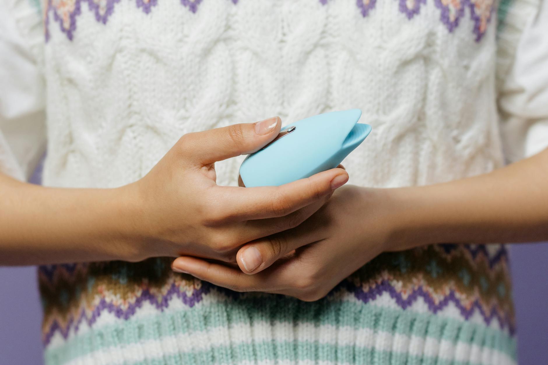 A young couple holding a blue clitoral vibrator together, symbolizing modern intimacy and shared pleasure