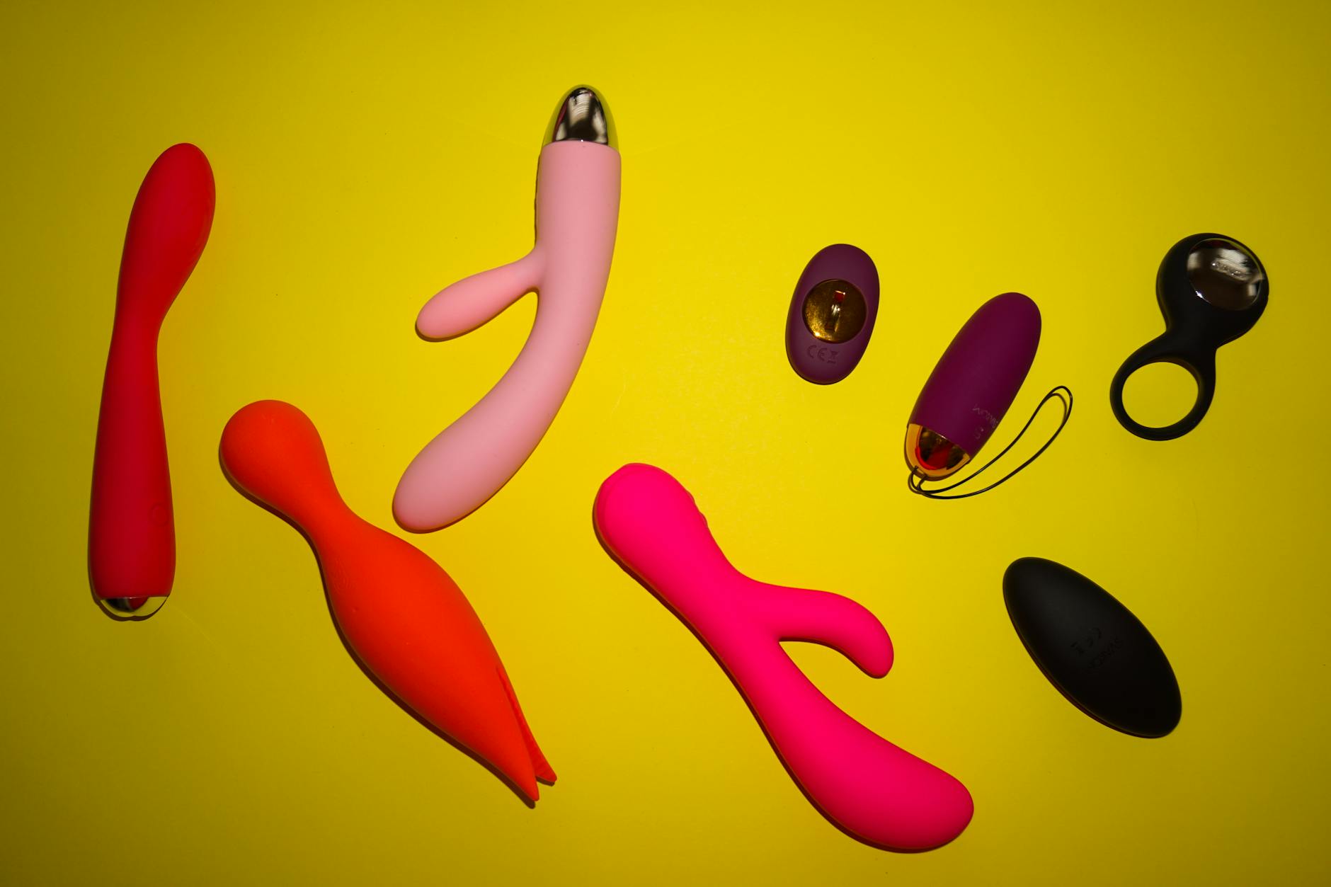 Woman holding blue and pink silicone vibrators with contemplative expression